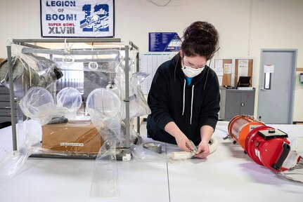 Sarah Higgins, a fabric worker with Shop 64, Sail Loft, installs a vacuum hose for the negative pressure air handling system on a prototype biocontainment system May 11, 2020 in Building 460, at Puget Sound Naval Shipyard & Intermediate Maintenance Facility in Bremerton, Washington.