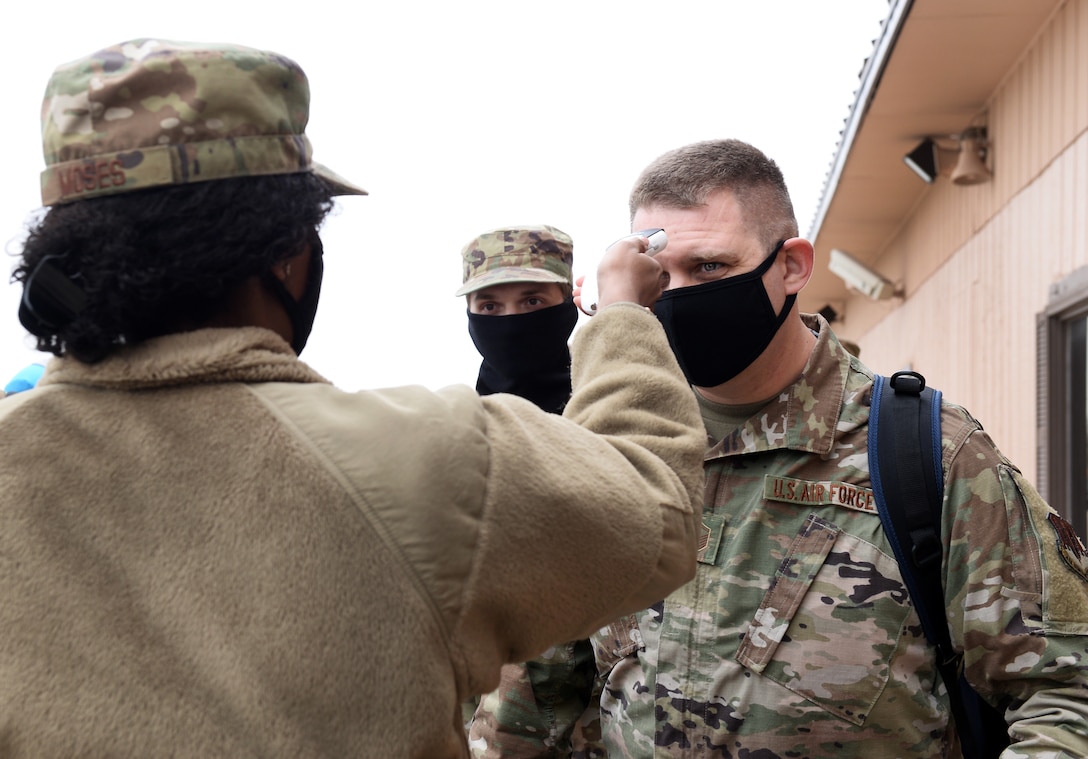 Airmen takes temperature of military member