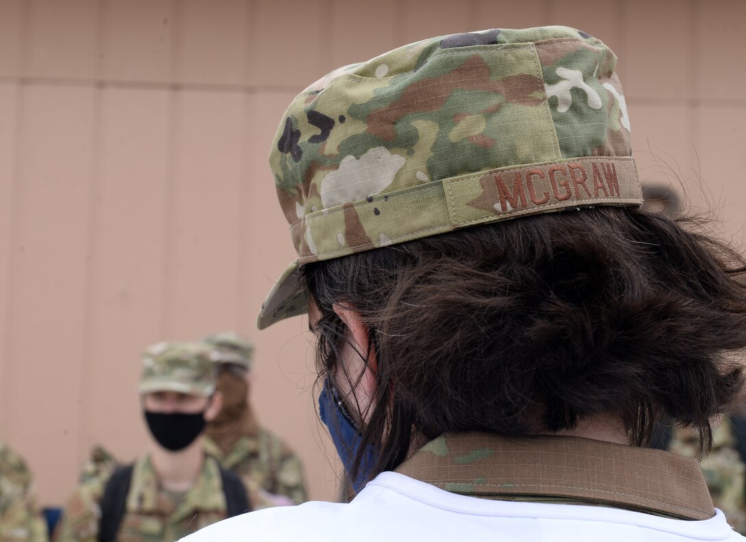 Woman brief other military members wearing mask during COVID-19 pandemic.
