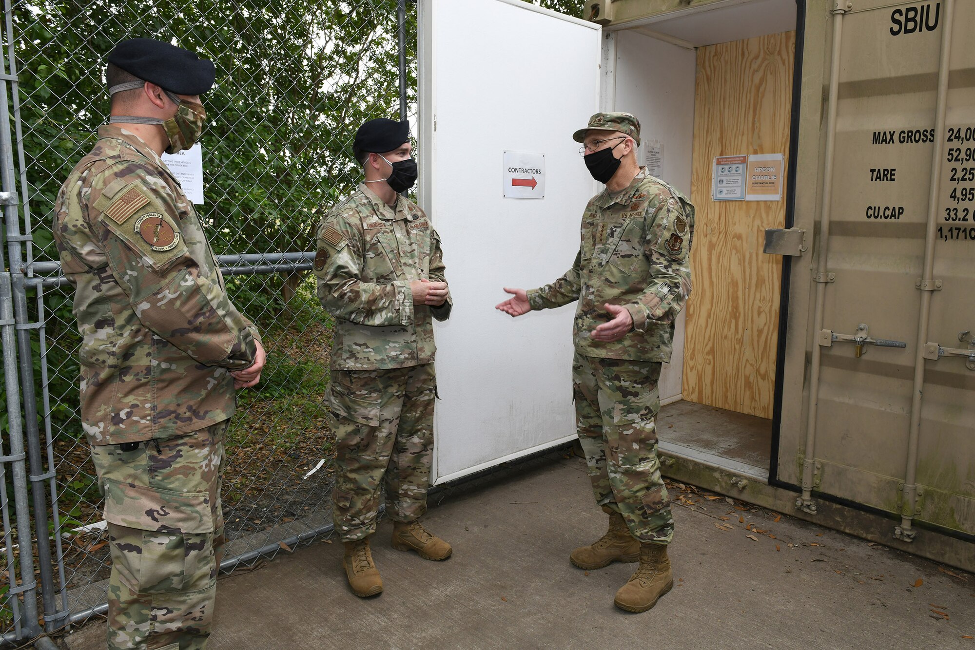 Photo shows two security forces personnel talking with the general in front of a waiting area outside.