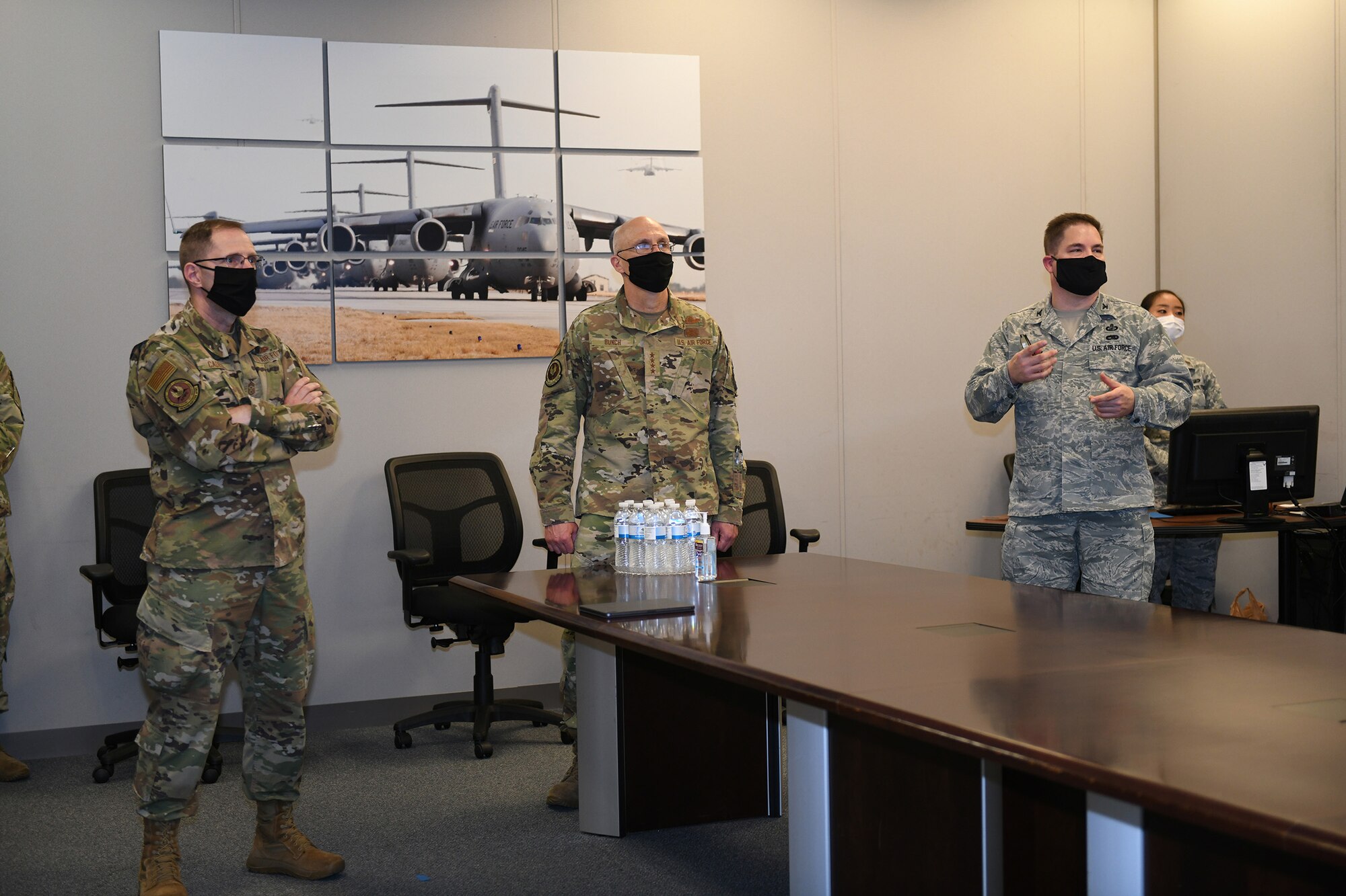 Photo shows the general and chief standing at the head of a conference table with the colonel briefing them.