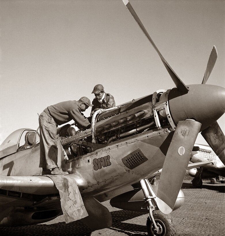 Two soldiers can be seen looking inside a P-51 Mustang