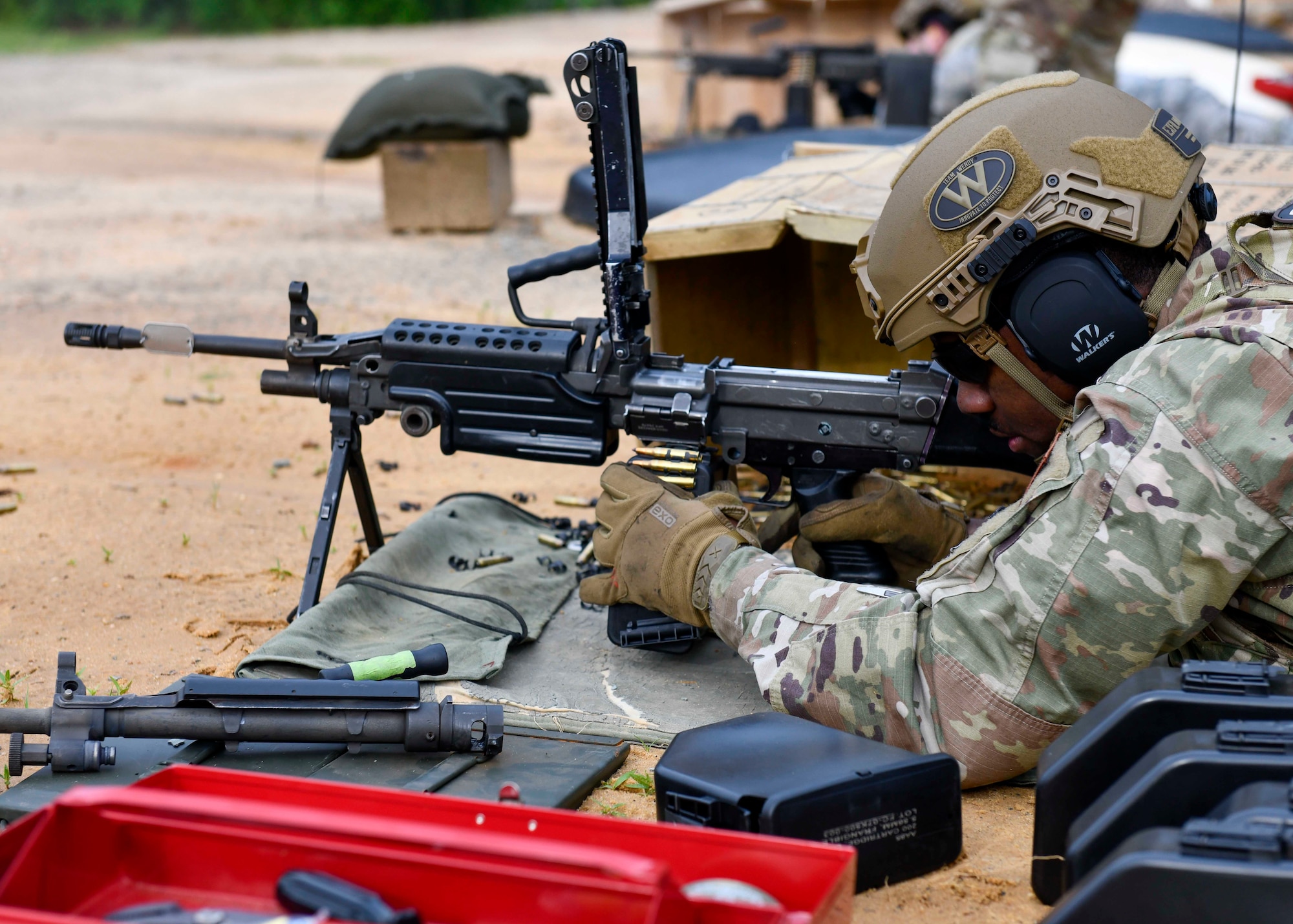 Senior Airman Marquez Roquemore, 4th Security Forces Squadron patrolman, loads an M249 light machine gun at Fort Bragg, North Carolina, May 6, 2020. Ammunition feeds into the weapon from a 200-round ammunition box containing a disintegrating, metallic split-link belt. (U.S. Air Force photo by Airman First Class Kimberly Barrera)