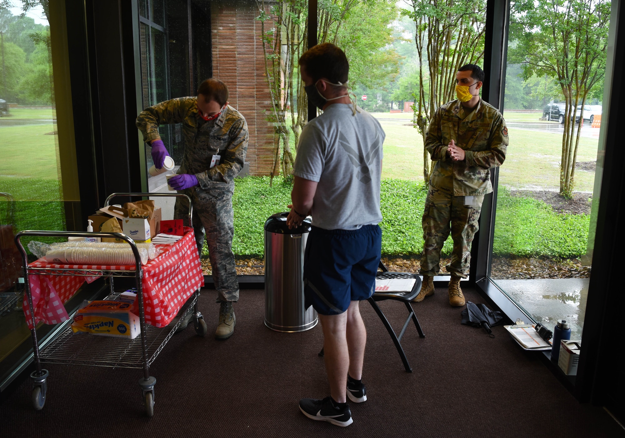 Second Lt. Ian Diebert (left), 14th Operational Medical Readiness Squadron casual, pours coffee for incoming personnel at the entrance of the Koritz Clinic May 8, 2020, on Columbus Air Force Base, Miss. Due to the potential stress enhancers that COVID-19 has caused, the 14th Blaze Medics Morale Council has been consistently looking for ways to uplift the morale within the 14th Medical Group. (U.S. Air Force photo by Airman 1st Class Jake Jacobsen)