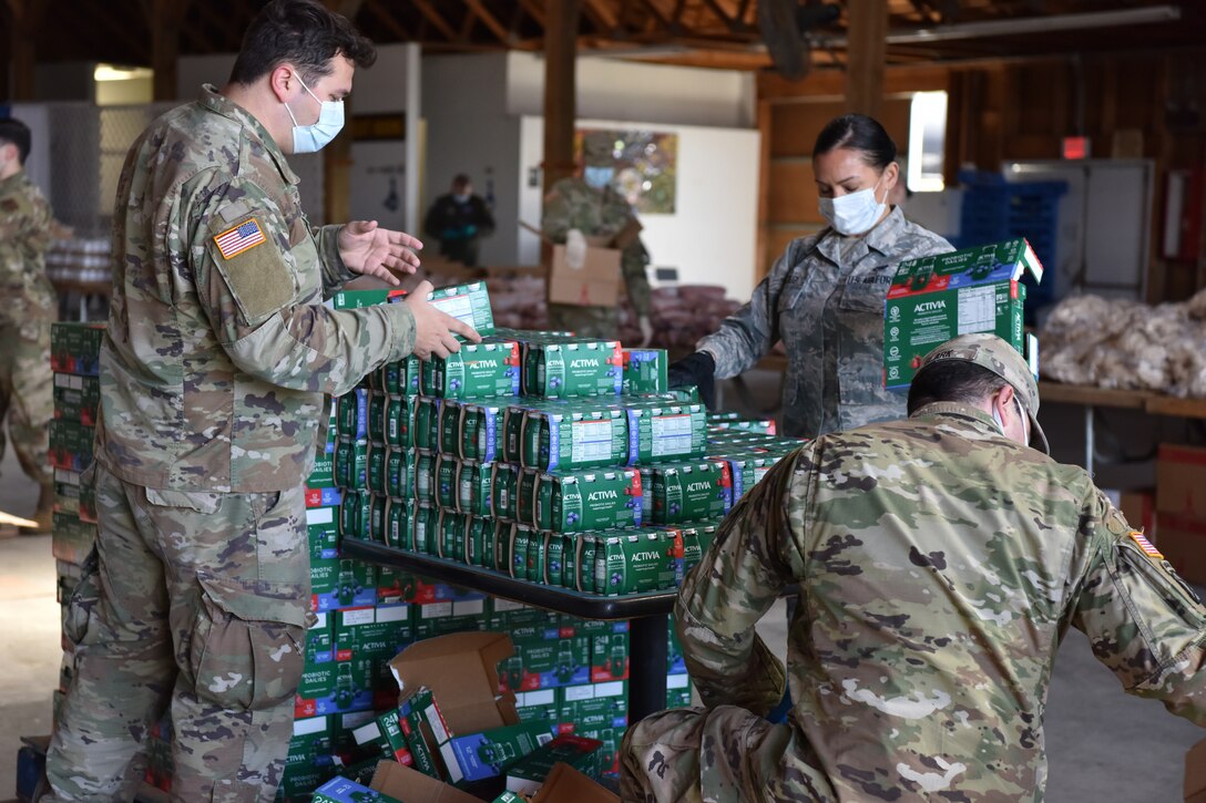 A group of soldiers unpack food onto a table.