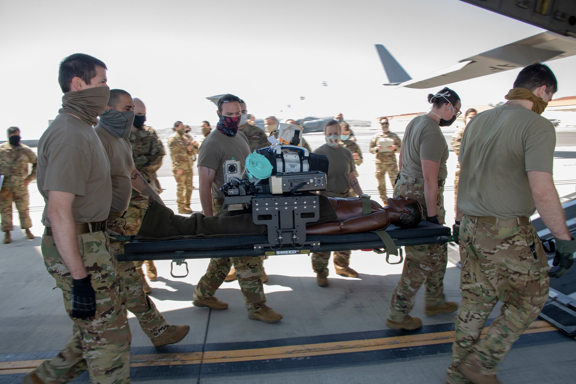 U.S. Air Force COVID West Aeromedical Evacuation Task Force members carry a medical mannequin onto a C-17 Globemaster III during a training exercise May 7, 2020, at Travis Air Force Base, California. The training focused on receiving and caring for potential COVID-19 patients using Transport Isolation System capsules. Travis AFB has a - C-17 loaded with a TIS capsule on alert status to ensure the aircraft is ready to launch at a moment’s notice. The TIS unit allows the transport of individuals with highly contagious diseases without infecting other passengers or aircrew on the aircraft. (U.S. Air Force photo by Heide Couch)