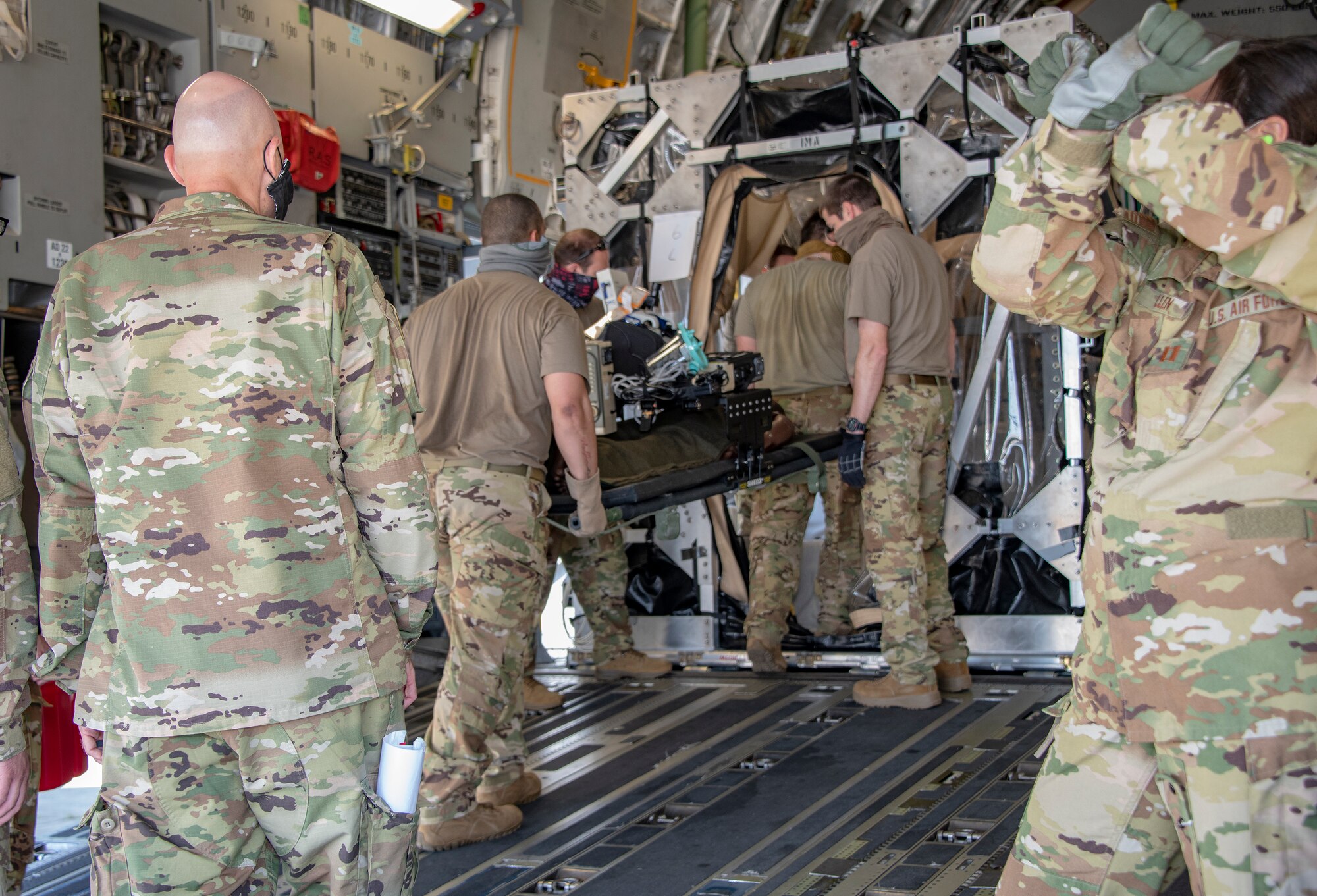 U.S. Air Force COVID West Aeromedical Evacuation Task Force place a medical mannequin into a Transport Isolation System capsule aboard a C-17 Globemaster III during a training exercise May 7, 2020, at Travis Air Force Base, California. The training focused on receiving and caring for potential COVID-19 patients using TIS capsules. Travis AFB has a - C-17 loaded with a TIS capsule on alert status to ensure the aircraft is ready to launch at a moment’s notice. The TIS unit allows the transport of individuals with highly contagious diseases without infecting other passengers or aircrew on the aircraft. (U.S. Air Force photo by Heide Couch)