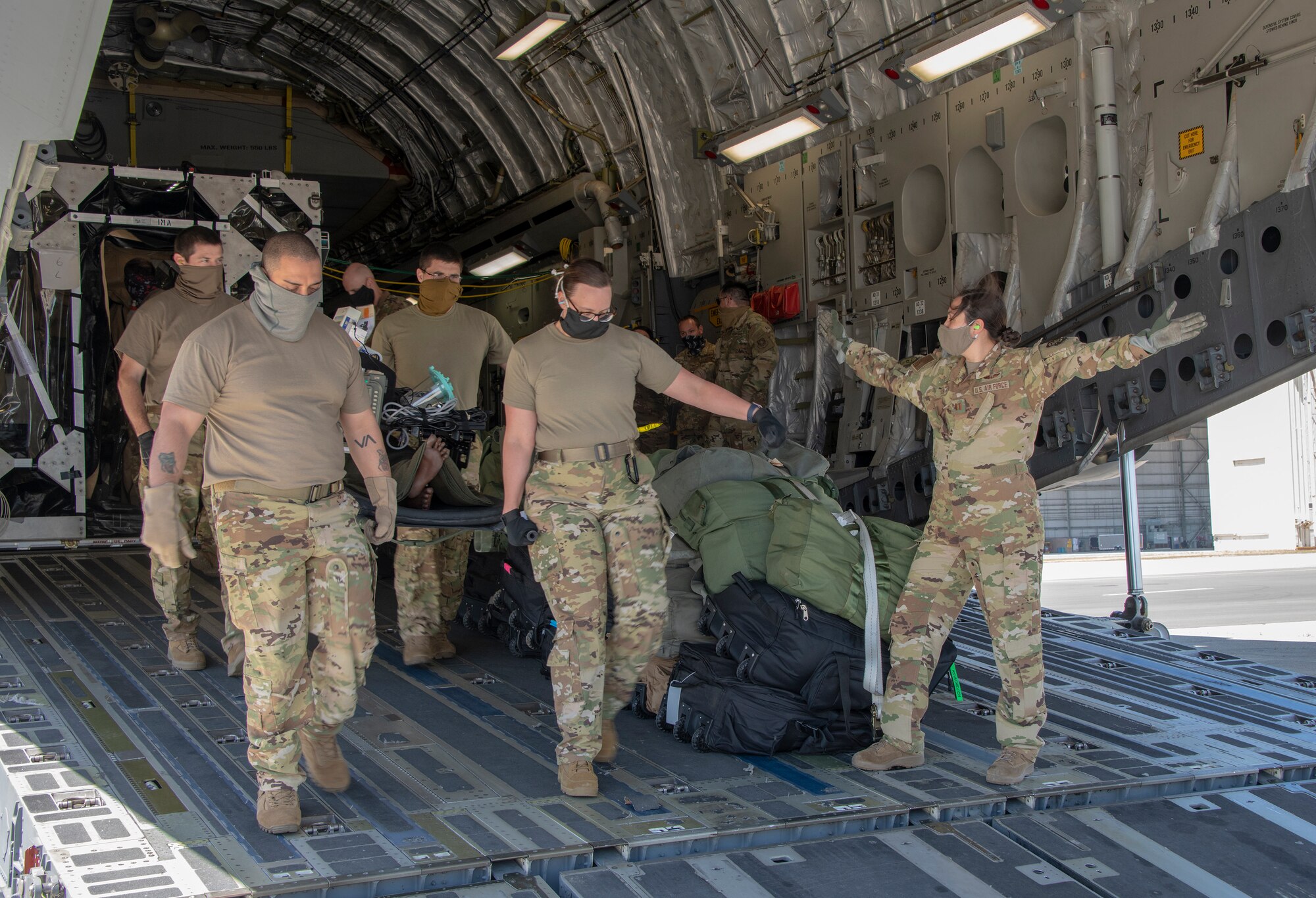U.S. Air Force COVID West Aeromedical Evacuation Task Force members carry a medical mannequin off a C-17 Globemaster III May 7, 2020, at Travis Air Force Base, California. The training focused on receiving and caring for potential COVID-19 patients using Transport Isolation System capsules. Travis AFB has a - C-17 loaded with a TIS capsule on alert status to ensure the aircraft is ready to launch at a moment’s notice. The TIS unit allows the transport of individuals with highly contagious diseases without infecting other passengers or aircrew on the aircraft. (U.S. Air Force photo by Heide Couch)