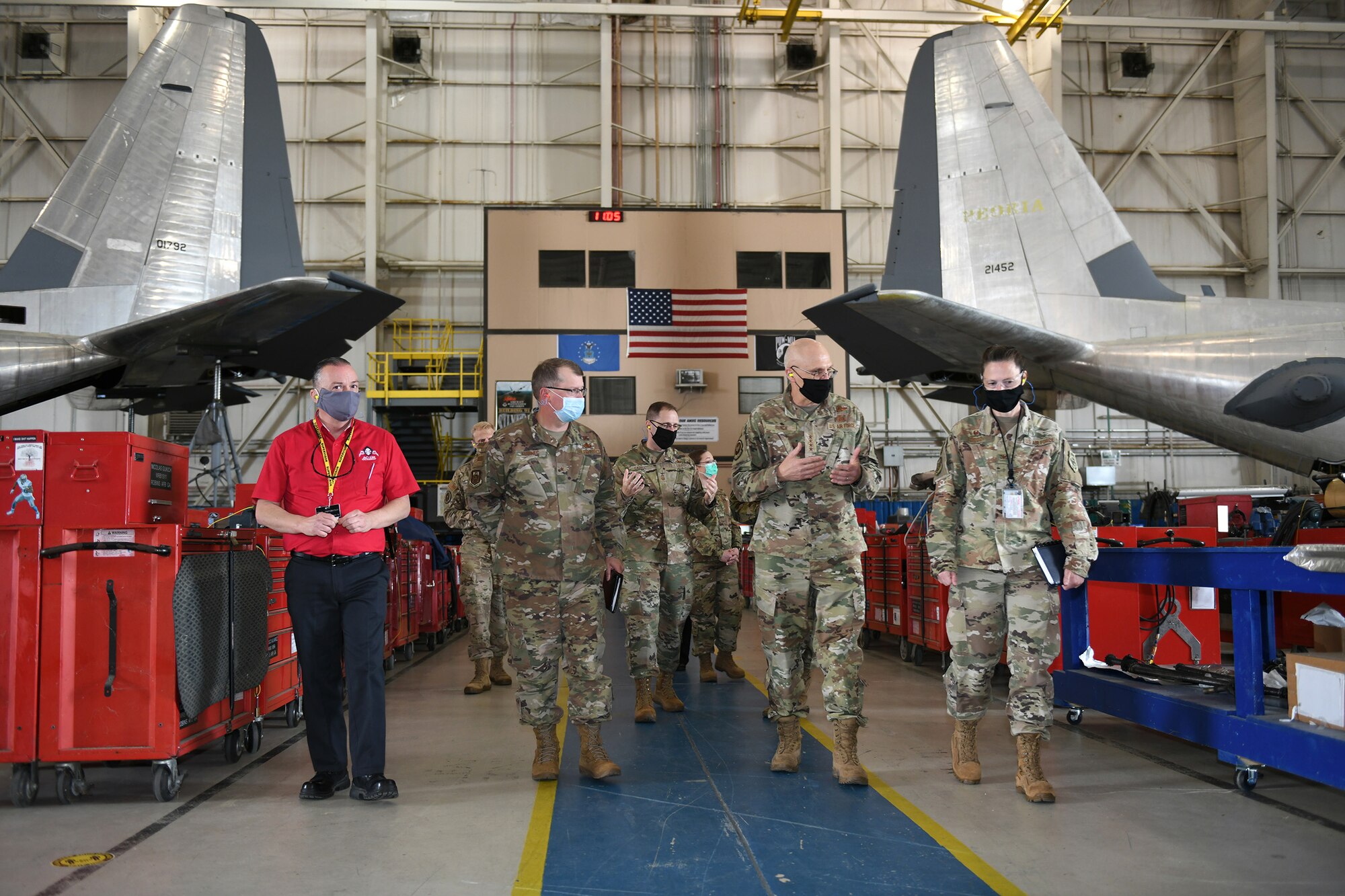 Photo shows Bunch walking with a group of Robins personnel with the tails of two C-130 aircraft in the background.
