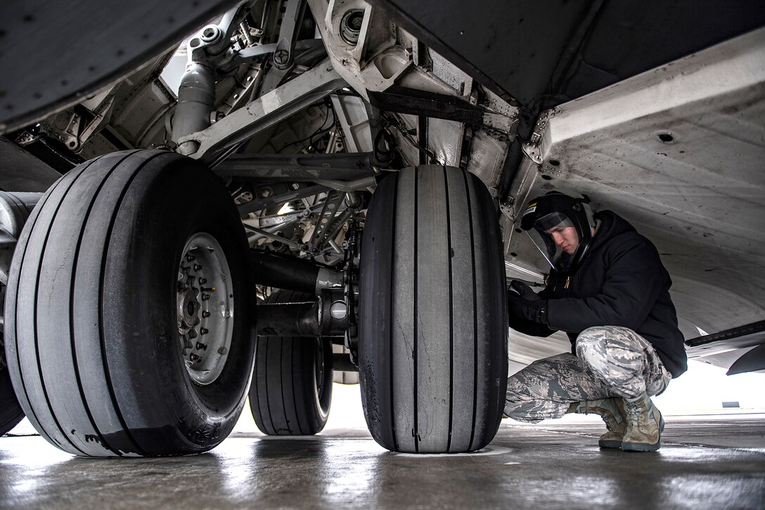 An airman checks the tire pressure on a large military aircraft.