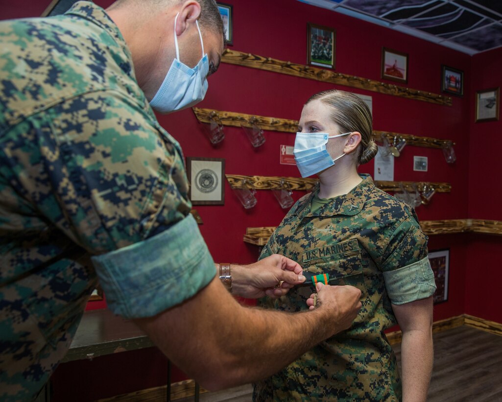 (Right) U.S. Marine Corps Lance Cpl. Zeelie Scruggs, an intelligence specialist with 2nd Intelligence Battalion, II Marine Expeditionary Force Information Group, is awarded a Navy and Marine Corps Achievement Medal at Camp Lejeune, N.C., May 8, 2020. Scruggs earned this medal for her volunteer service to the local community during the Coronavirus pandemic from March to April 2020. (U.S. Marine Corps photo by Cpl. Stephen Campbell)