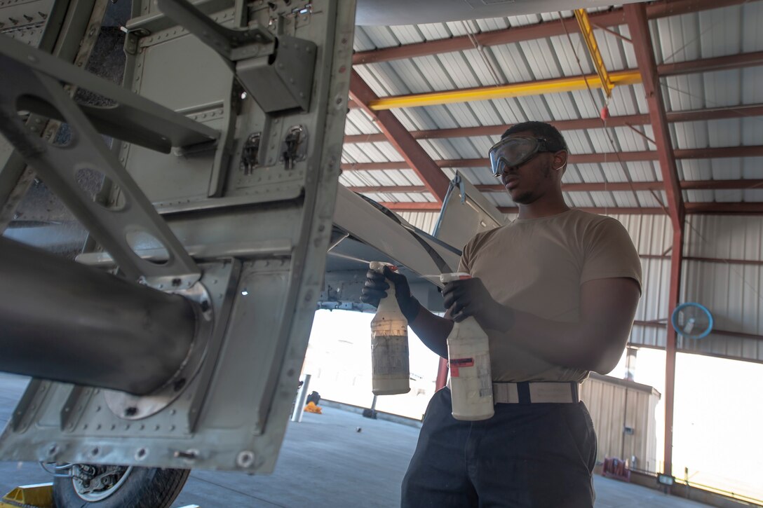 A photo of an Airman spraying an aircraft with spray bottles