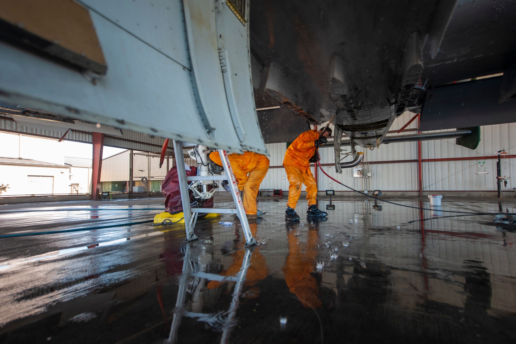 A photo of an Airman spraying the bottom of an aircraft