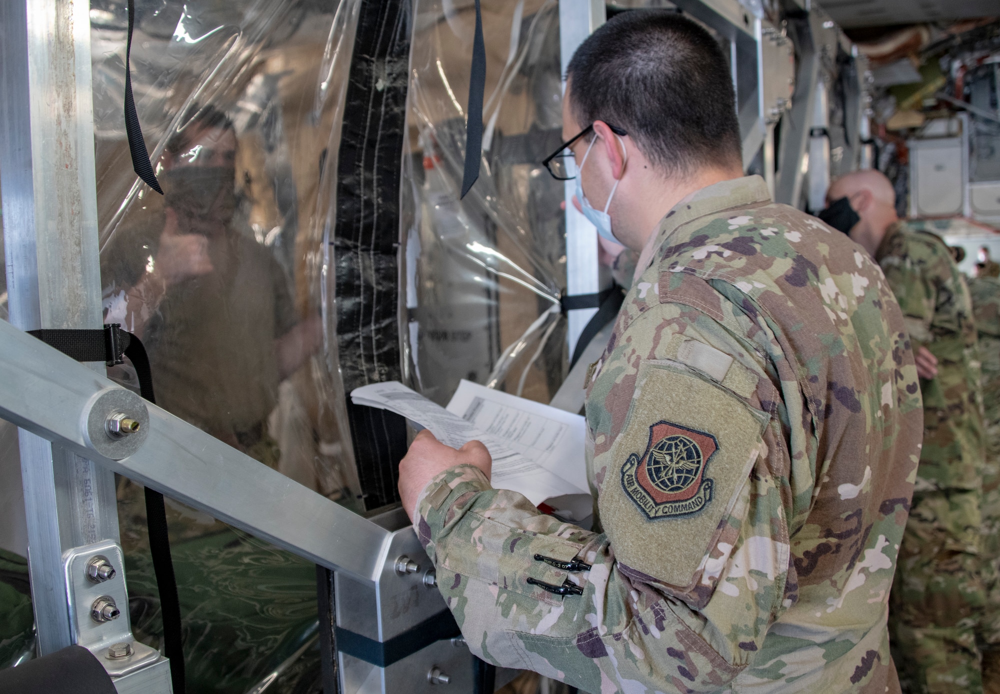 U.S. Air Force COVID West Aeromedical Evacuation Task Force members practice sanitation procedures while in a Transport Isolation System capsule aboard a C-17 Globemaster III during a training exercise May 7, 2020, at Travis Air Force Base, California. The training focused on receiving and caring for potential COVID-19 patients using TIS capsules. Travis AFB has a - C-17 loaded with a TIS capsule on alert status to ensure the aircraft is ready to launch at a moment’s notice. The TIS unit allows the transport of individuals with highly contagious diseases without infecting other passengers or aircrew on the aircraft. (U.S. Air Force photo by Heide Couch)