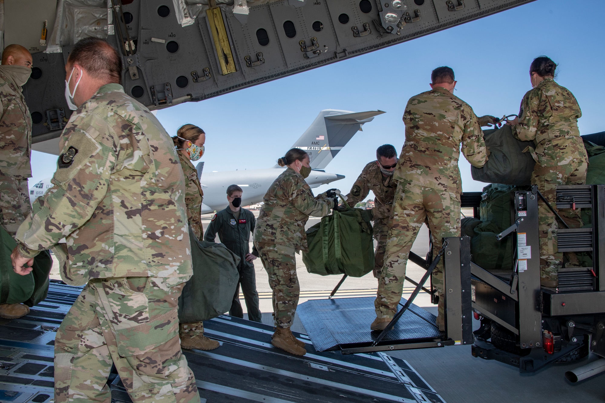 U.S. Air Force COVID West Aeromedical Evacuation Task Force members off load baggage from a C-17 Globemaster III during a training exercise May 7, 2020, at Travis Air Force Base, California. The training focused on receiving and caring for potential COVID-19 patients using Transport Isolation System capsules. Travis AFB has a - C-17 loaded with a TIS capsule on alert status to ensure the aircraft is ready to launch at a moment’s notice. The TIS unit allows the transport of individuals with highly contagious diseases without infecting other passengers or aircrew on the aircraft. (U.S. Air Force photo by Heide Couch)