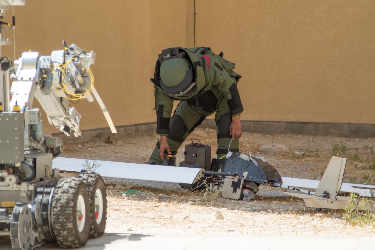 A soldier examines a simulated downed unmanned aerial vehicle during an exercise.