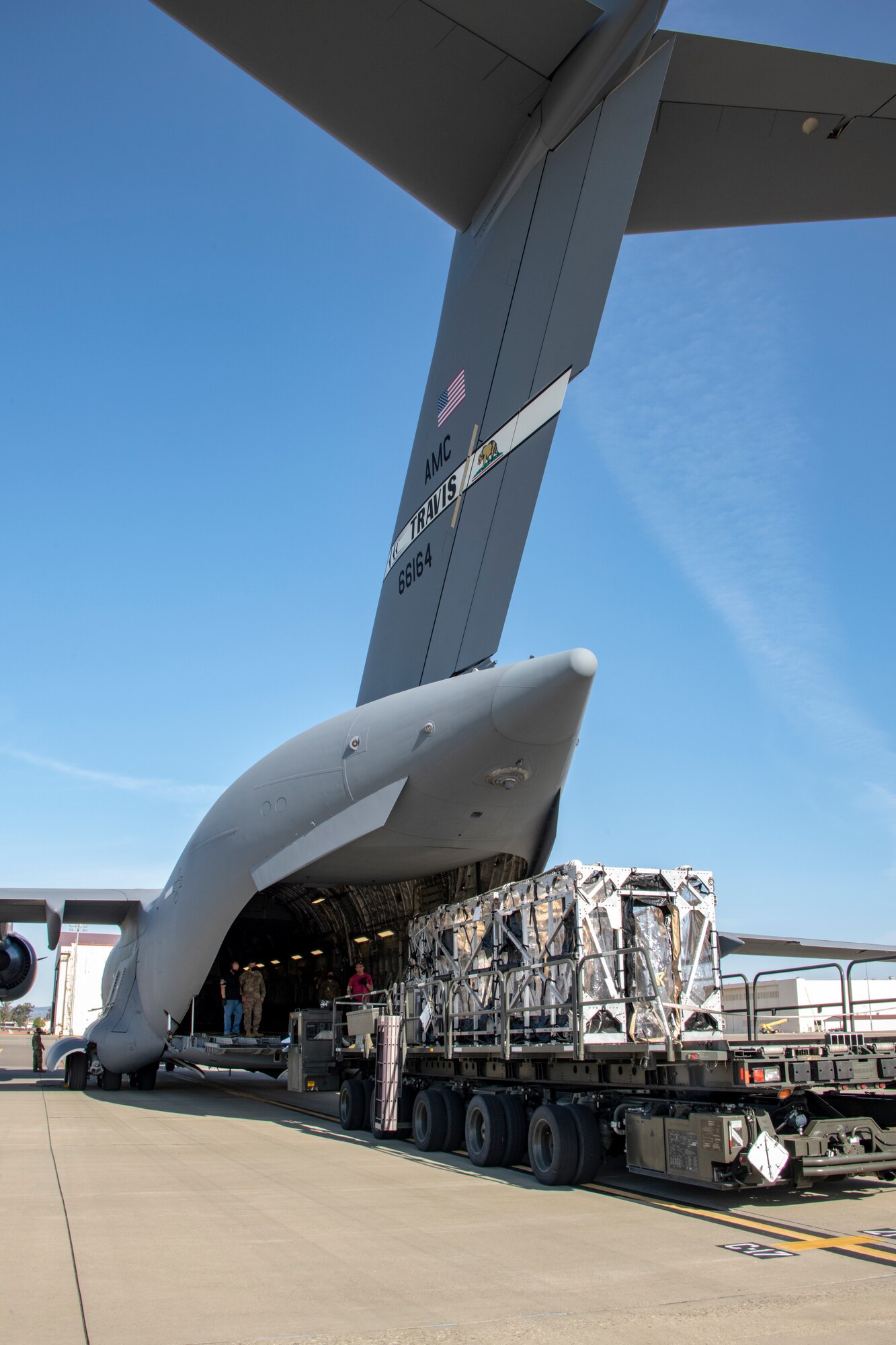 Personnel from the 60th Aerial Port Squadron transfer a Transport Isolation System capsule from a Tunner 60K loader into the cargo bay of a C-17 Globemaster III May 9, 2020, at Travis Air Force Base, California. The C-17, C-130H Hercules and C-130J Super Hercules are the only aircraft capable of carrying TIS capsules, which the DOD initially engineered in response to the Ebola virus in 2014. The capsules allow the transport of individuals with highly contagious diseases without infecting any other passengers or aircrew on the aircraft. (U.S. Air Force photo by Heide Couch)