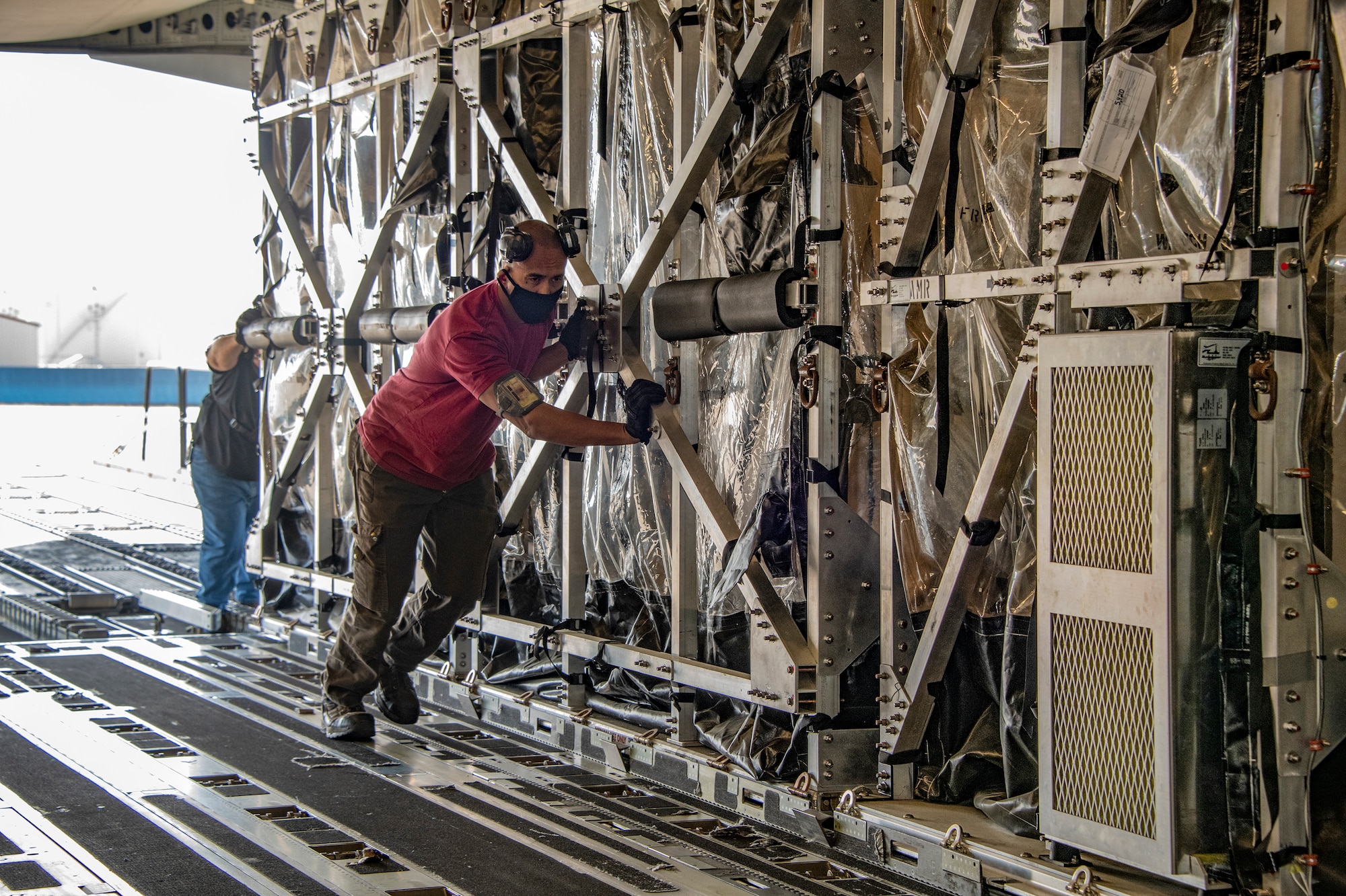 Ramon Duenas, 60th Aerial Port Squadron expediter load director, helps push a Transport Isolation System capsule into the cargo bay of a C-17 Globemaster III May 9, 2020, at Travis Air Force Base, California. Travis AFB has a C-17 loaded with a TIS capsule on alert status to ensure the aircraft is ready to launch at a moment’s notice. The TIS unit allows the transport of individuals with highly contagious diseases without infecting other passengers or aircrew on the aircraft. (U.S. Air Force photo by Heide Couch)