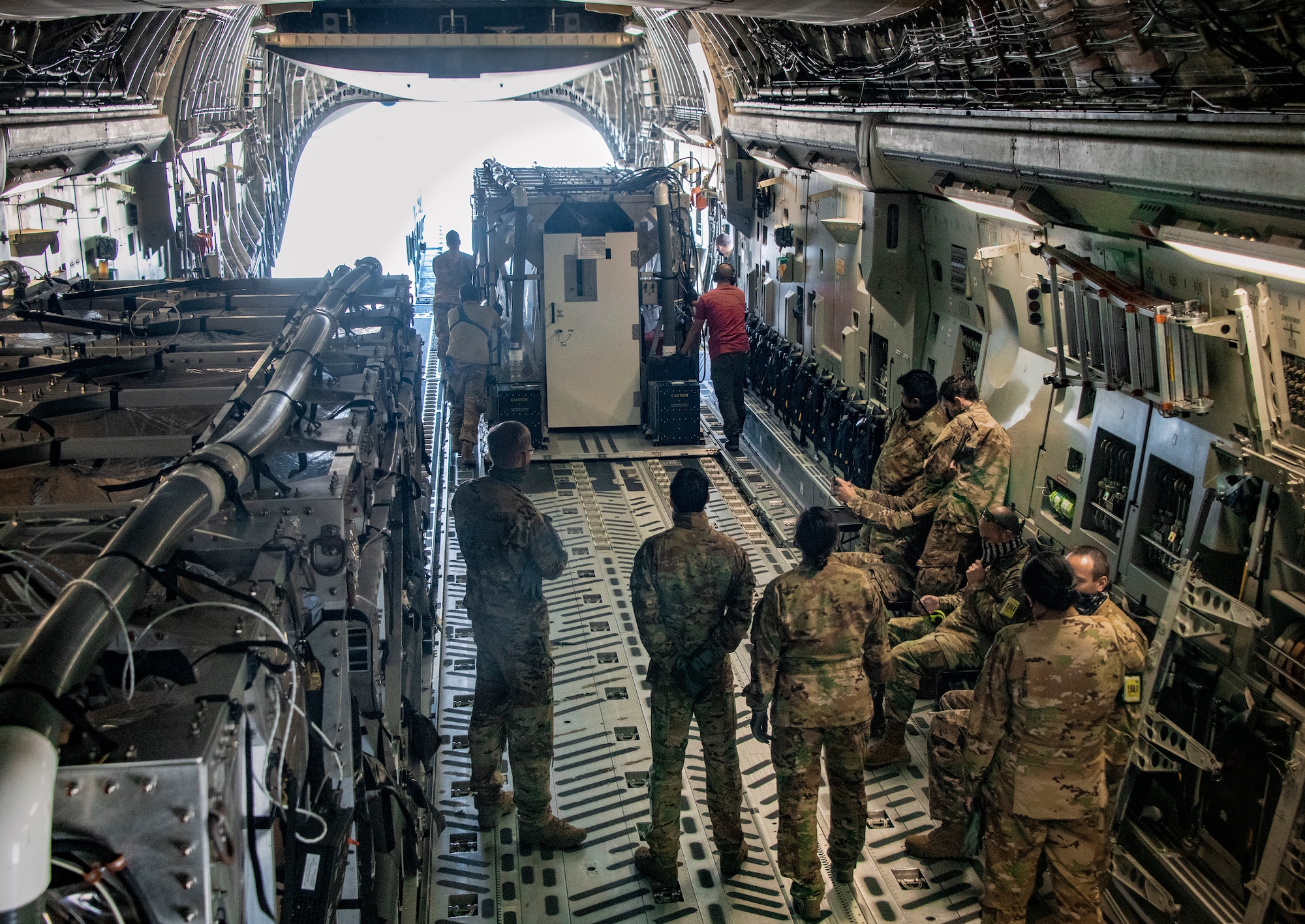 Personnel from the 60th Aerial Port Squadron and medical personnel from the COVID West Aeromedical Evacuation Task Force unload a Transport Isolation System capsule from the cargo bay of a C-17 Globemaster III May 9, 2020, at Travis Air Force Base, California. Travis AFB has a C-17 loaded with a TIS capsule on alert status to ensure the aircraft is ready to launch at a moment’s notice. The TIS unit allows the transport of individuals with highly contagious diseases without infecting other passengers or aircrew on the aircraft. (U.S. Air Force photo by Heide Couch)