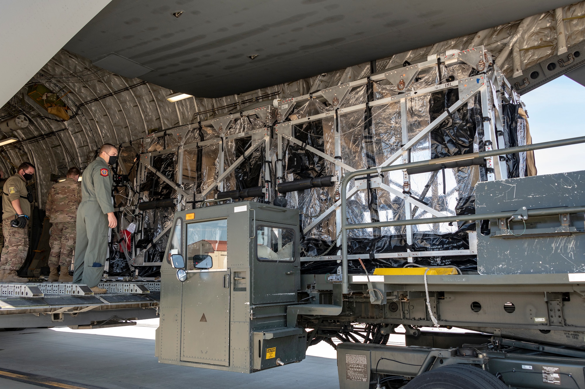 U.S. Air Force personnel from the 21st Airlift Squadron and 60th Aerial Port Squadron unload a Transport Isolation System capsule from the cargo bay of a C-17 Globemaster III May 9, 2020, at Travis Air Force Base, California. Travis AFB has a C-17 loaded with a TIS capsule on alert status to ensure the aircraft is ready to launch at a moment’s notice. The TIS unit allows the transport of individuals with highly contagious diseases without infecting other passengers or aircrew on the aircraft. (U.S. Air Force photo by Heide Couch)