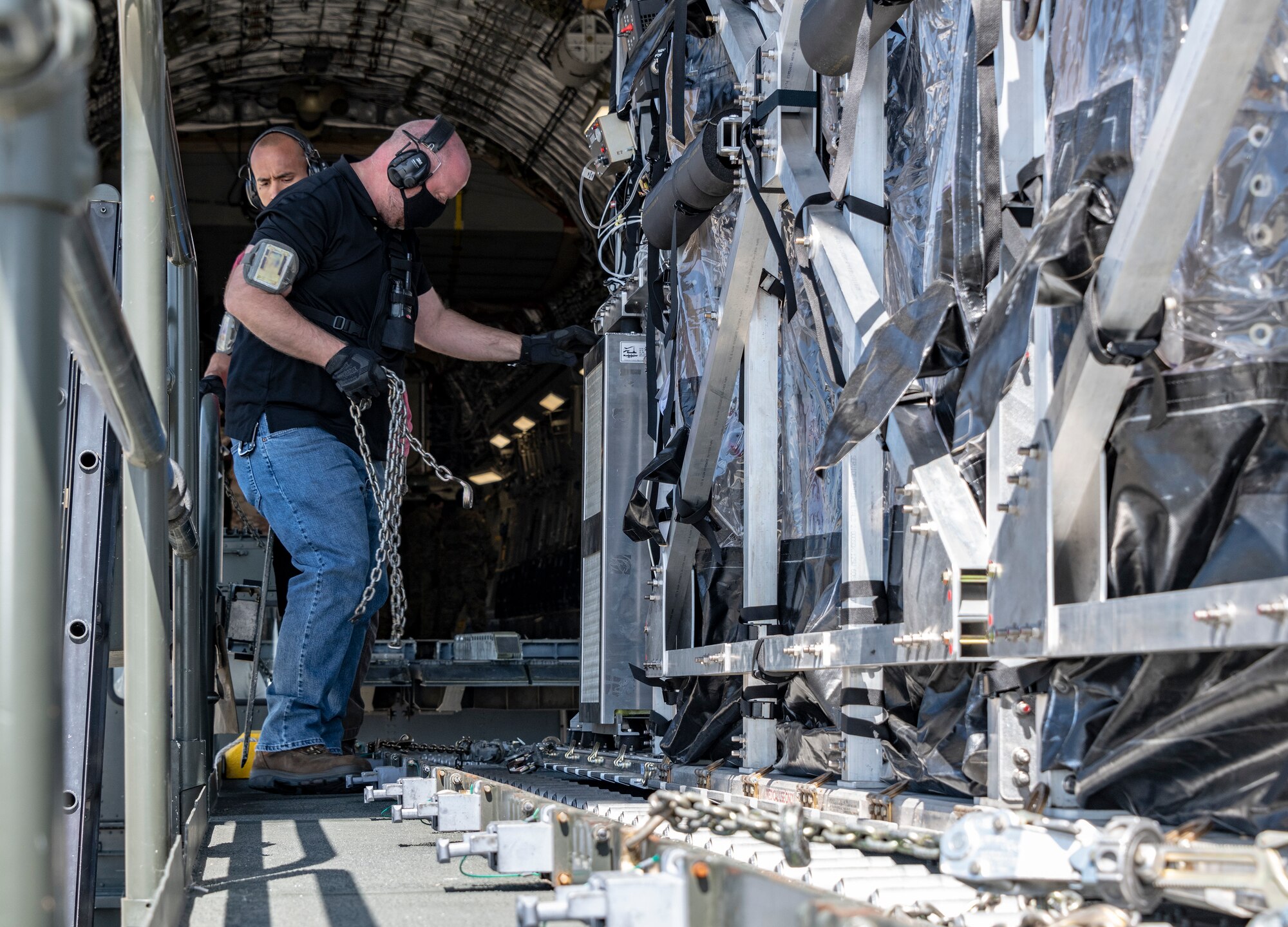 Vernon Kennedy, 60th Aerial Port Squadron loading supervisor, secures a Transport Isolation System capsule onto the deck of a Tunner 60K loader May 9, 2020, at Travis Air Force Base, California. Travis AFB has a C-17 loaded with a TIS capsule on alert status to ensure the aircraft is ready to launch at a moment’s notice. The TIS unit allows the transport of individuals with highly contagious diseases without infecting other passengers or aircrew on the aircraft. (U.S. Air Force photo by Heide Couch)