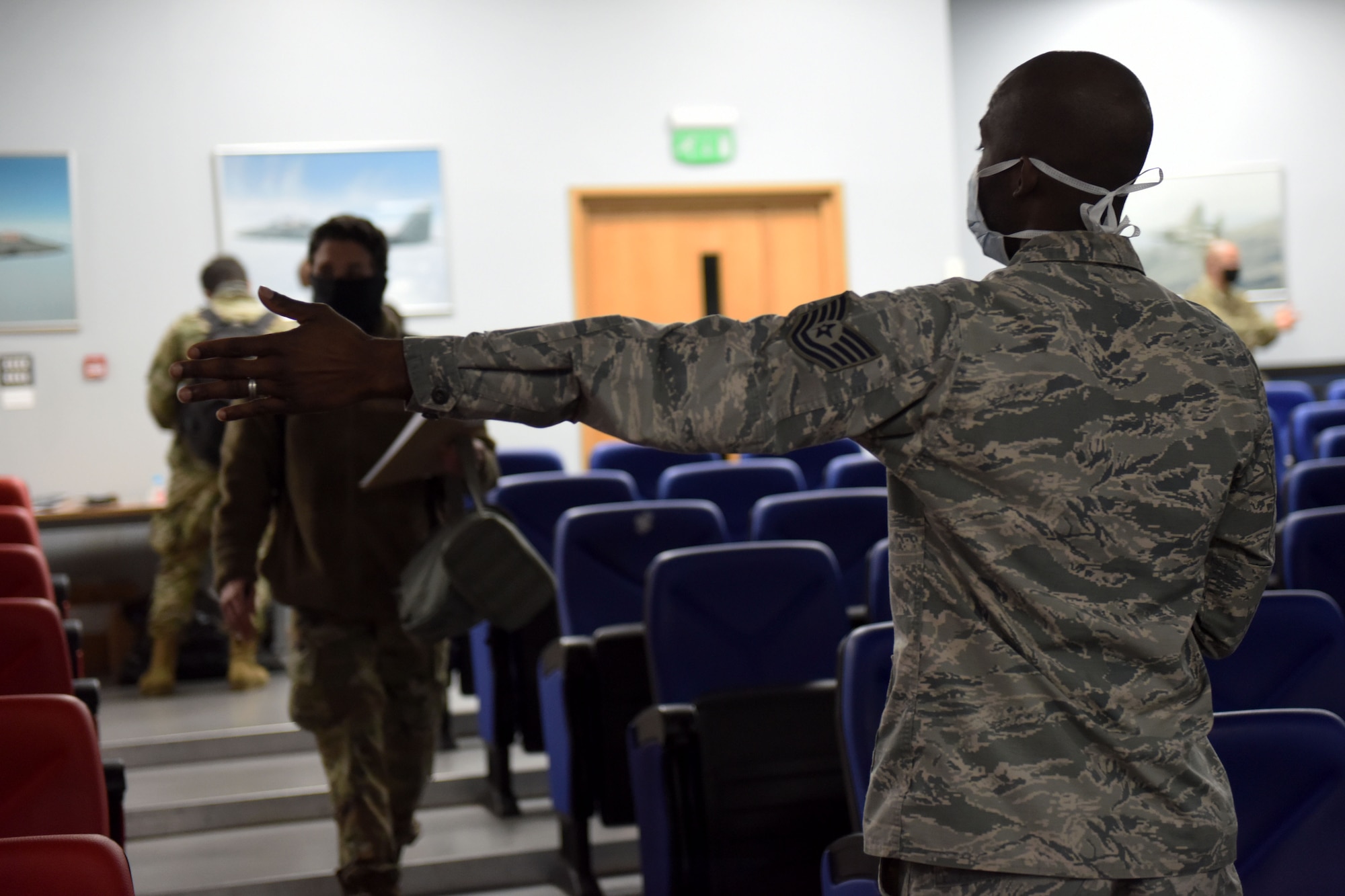A 48th Fighter Wing Airman directs 492nd Fighter Squadron Airmen to their seats in effort to maintain social distancing during a pre-deployment processing line at Royal Air Force Lakenheath, England, May 6, 2020. The 492nd FS is the first fighter squadron from the Liberty Wing to deploy since the start of the COVID-19 pandemic. (U.S. Air Force photo by Senior Airman Christopher S. Sparks)