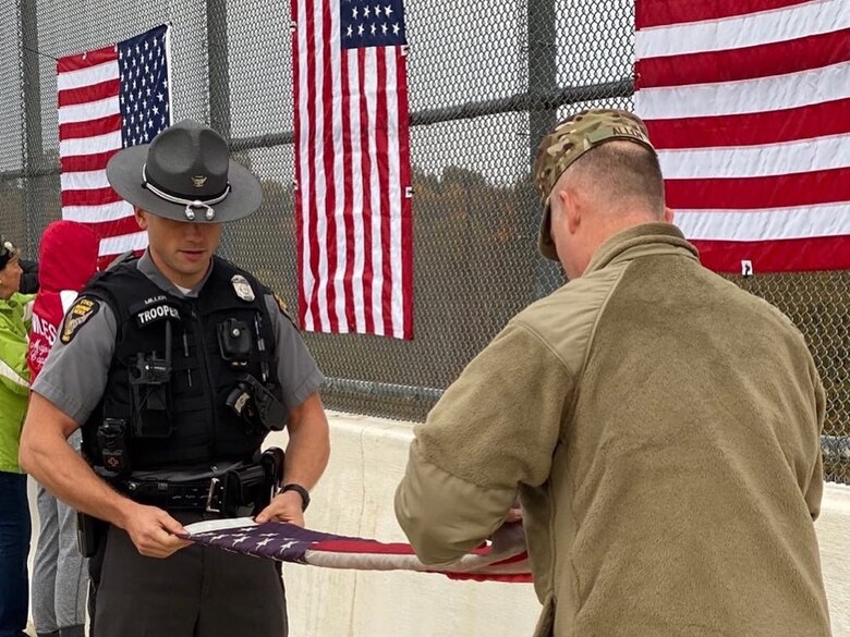 Staff Sgt. Brandon Miller, a heating, ventilation, air conditioning, and refrigeration (HVACR) technician at the 910th Civil Engineer Squadron and Ohio State Highway Patrolman at the Ashtabula post in Ohio, and Maj. Scott Allen, the public affairs officer for the 910th Airlift Wing, fold an American flag on the King Graves Road bridge, Oct. 26, 2019.