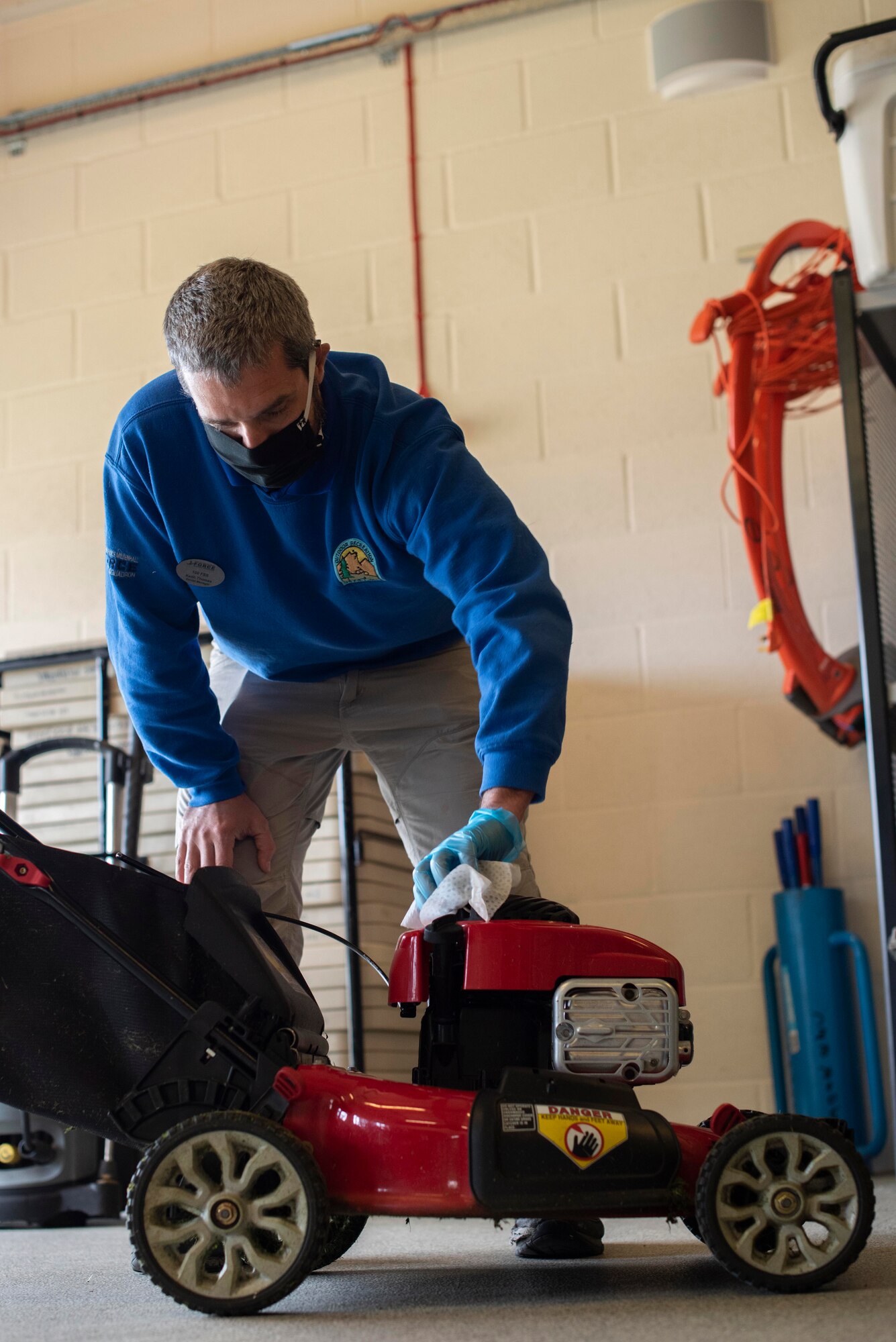 Keith Thomas, 100th Force Support Squadron Outdoor Recreation rental manager, sanitizes the top of a lawnmower inside the outdoor recreation center at RAF Mildenhall, England, May 11, 2020. To fight the spread of COVID-19, items returned from customers are thoroughly cleaned before being rented again. (U.S. Air Force photo by Airman 1st Class Joseph Barron)