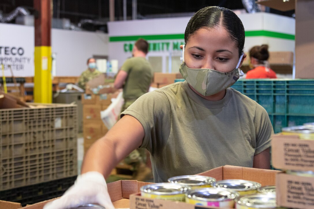 A soldier sorts through cans of food.