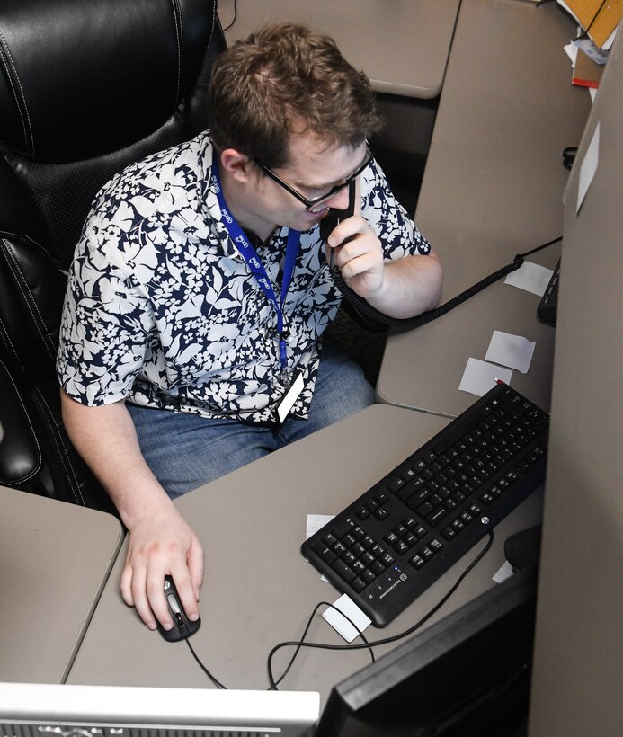 Keith Kinser, a Base Communications service desk team member, takes a customer call, May 5, 2020, at Arnold Air Force Base, Tenn. The AEDC Base Communications continues to provide support to AEDC during the coronavirus pandemic to ensure fellow AEDC team members have the communications resources necessary to fulfill the AEDC mission. They are utilizing social distancing and when that is not possible, masks, as risk mitigation measures. (U.S. Air Force photo by Jill Pickett)  (This image has been altered by obscuring items for security purposes.)