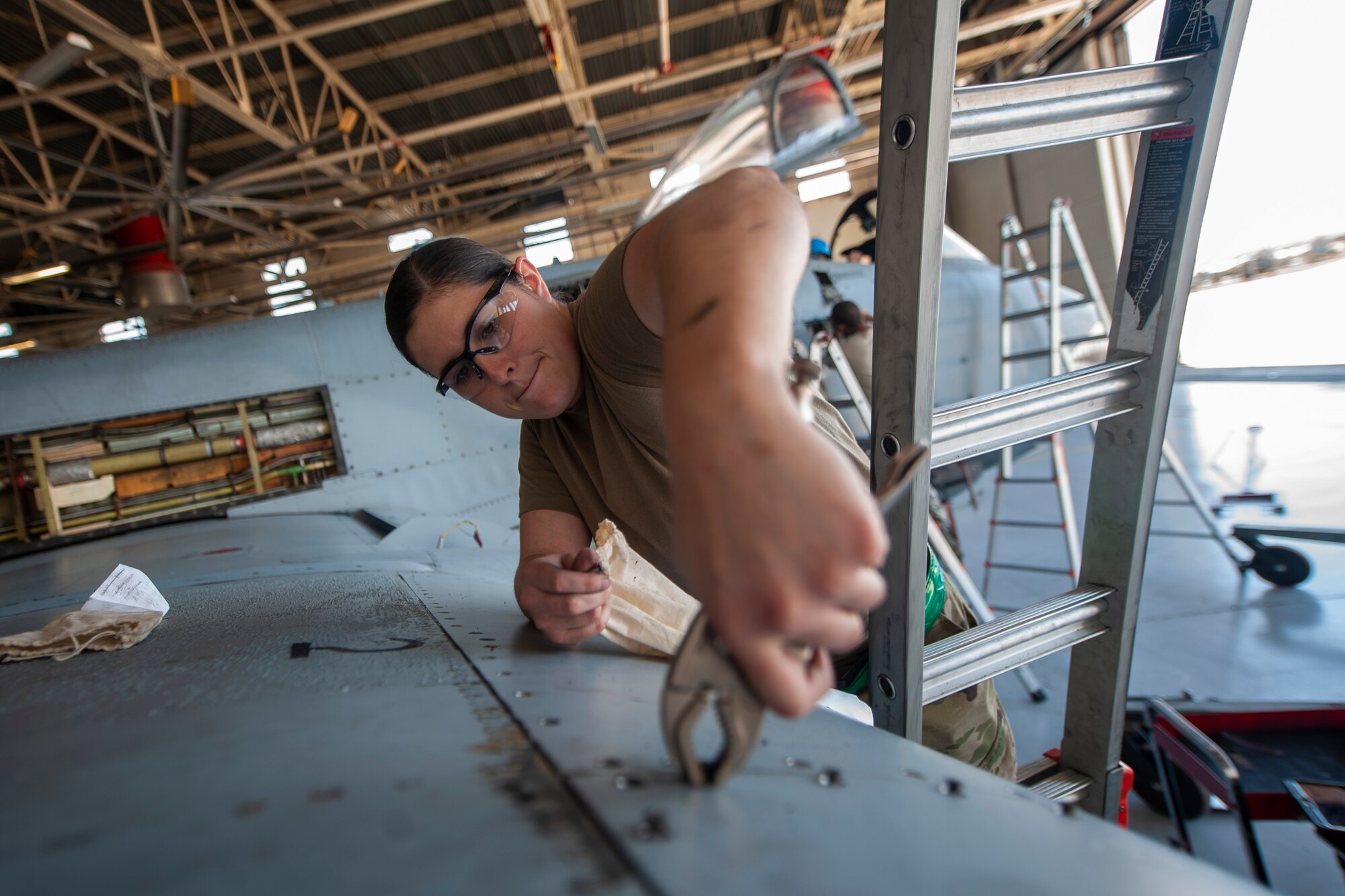 A photo of an Airman removing a bolt from an aircraft