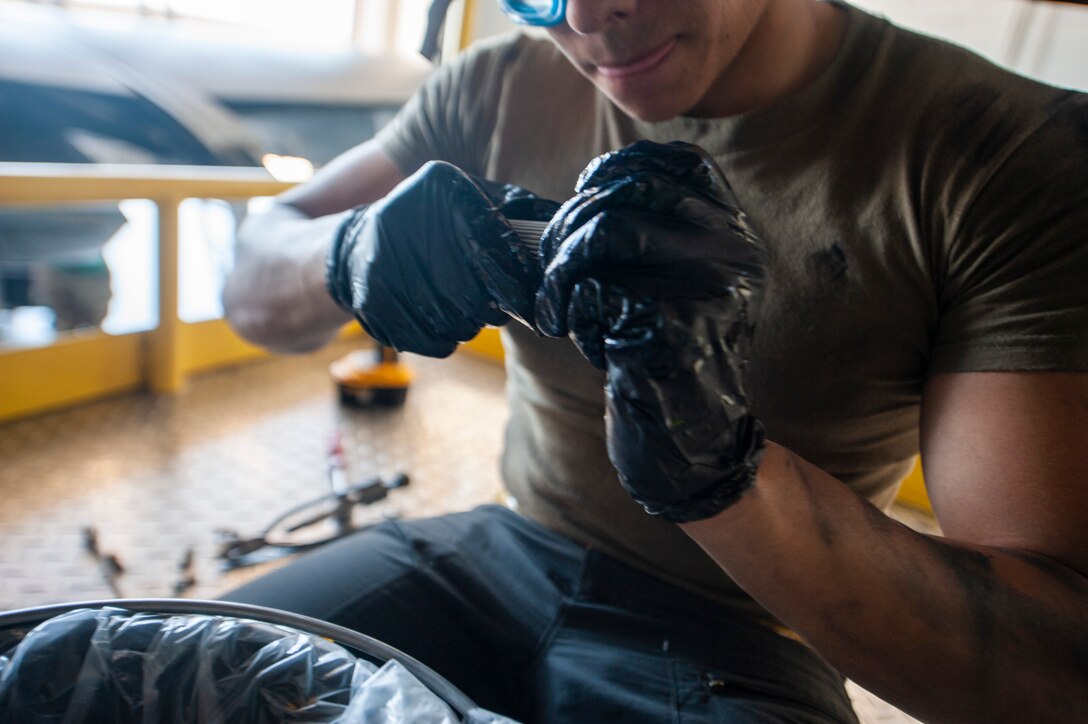 A photo of an Airman removing an aircraft component