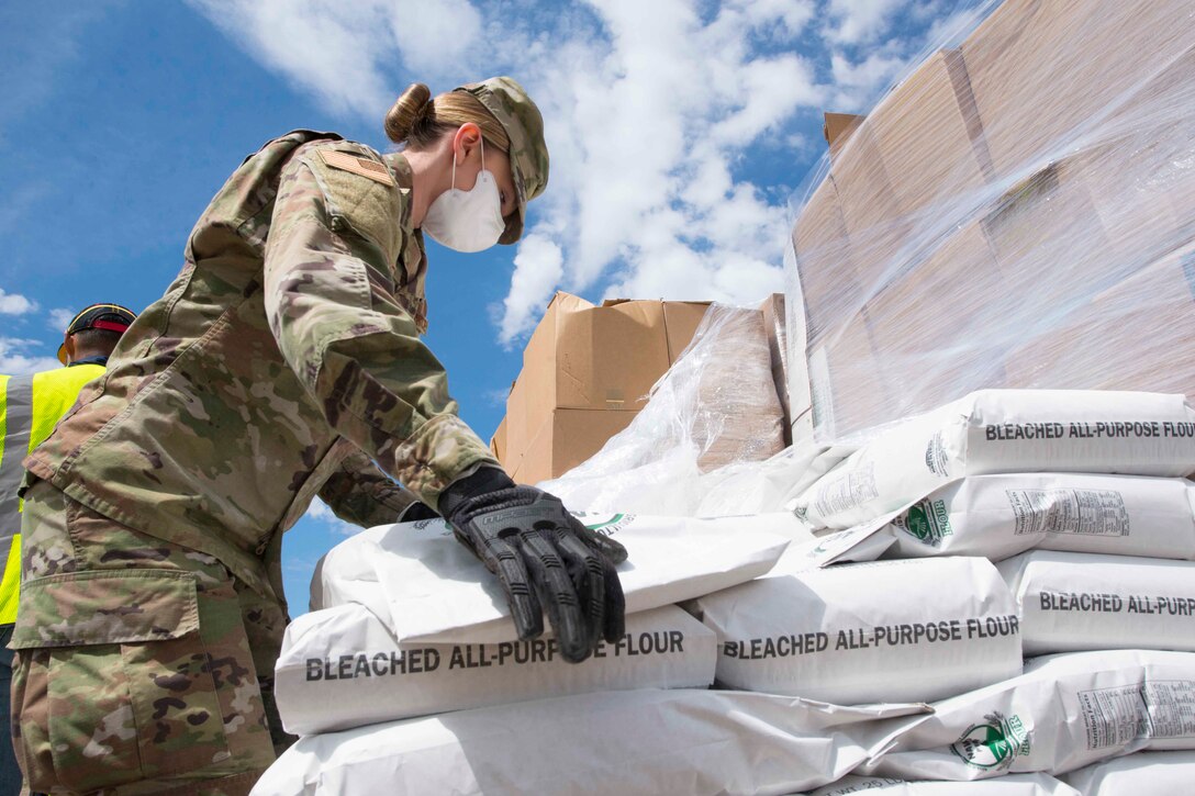 An airman moves packages of flour.