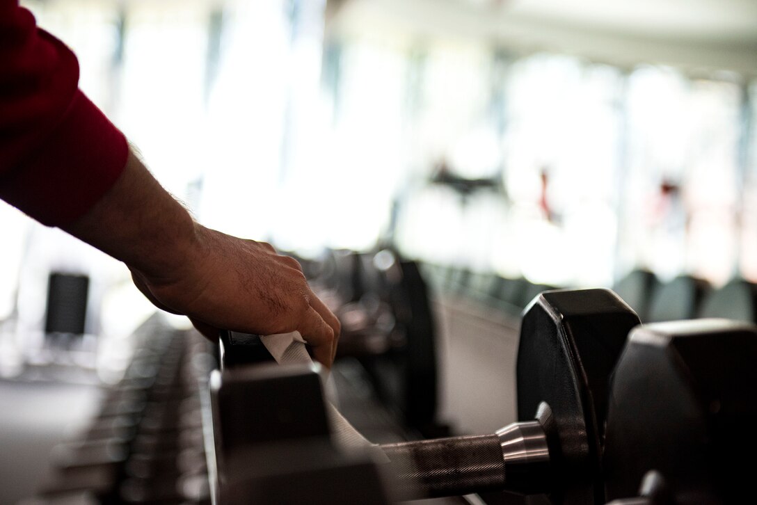 Photo of service member wiping down a dumbbell.