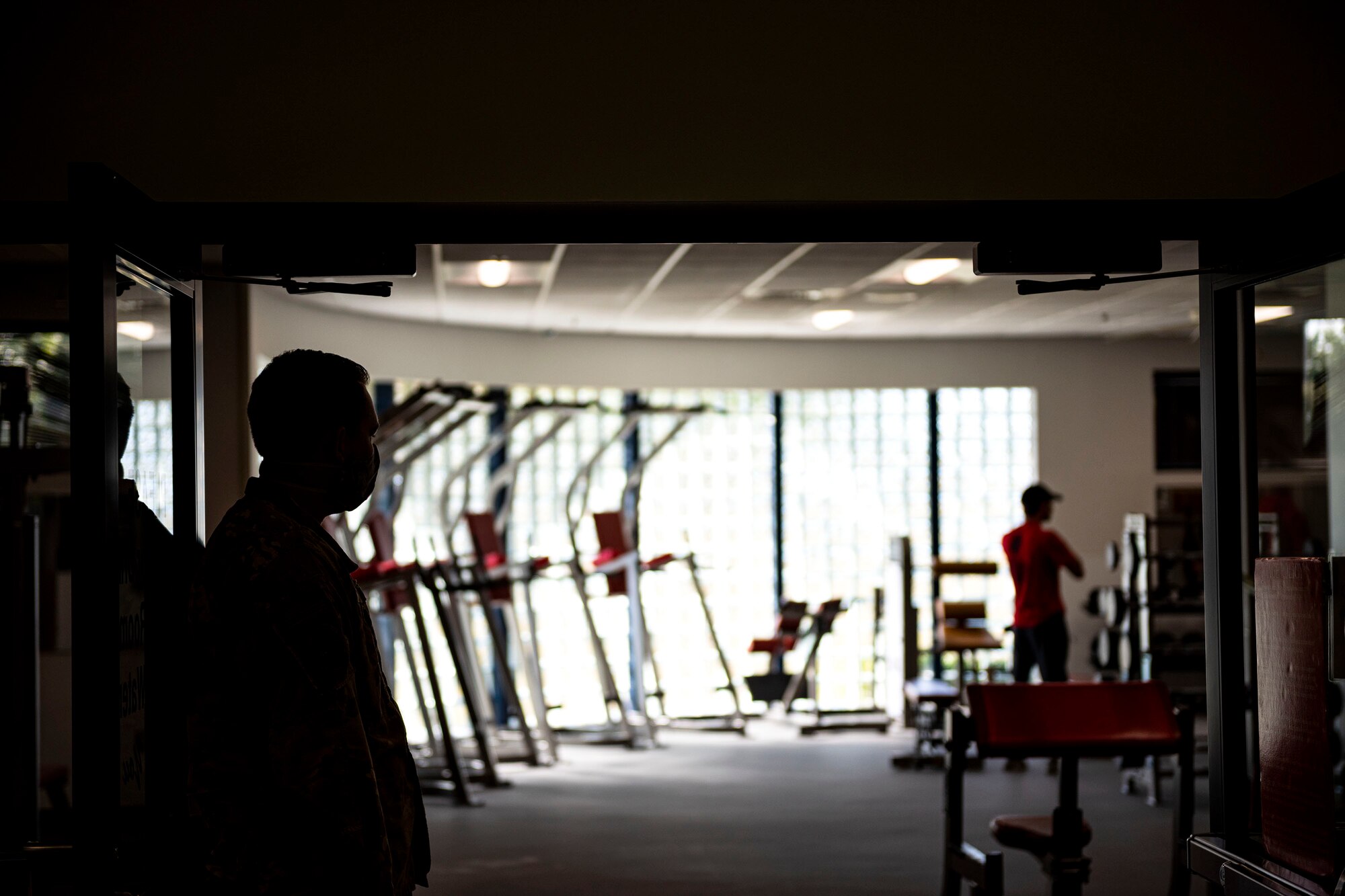 Photo of Airman observing service members adhering to health guidelines.