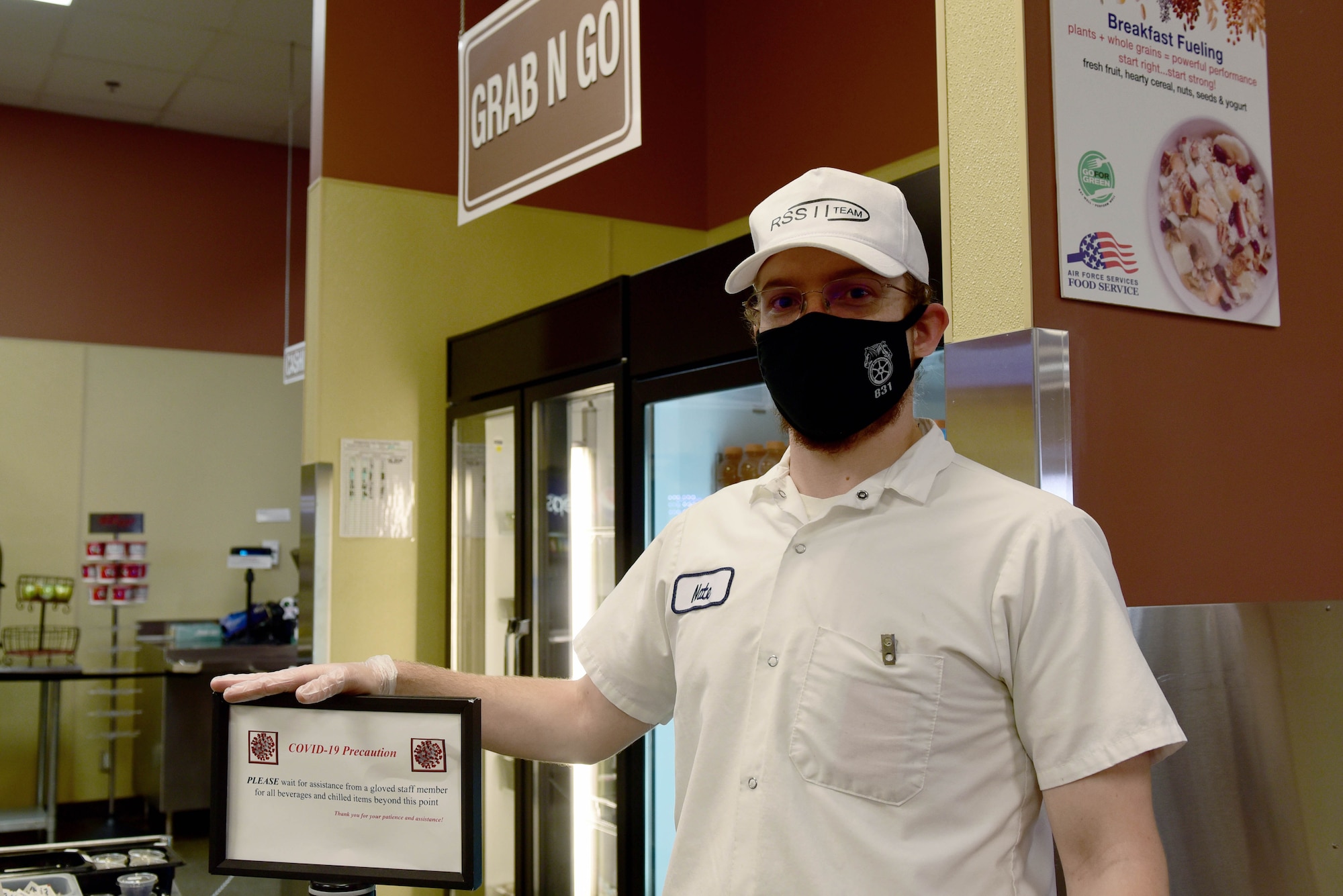 Nate Kramer, Guardian Dining Facility (DFAC) food service worker, stands with a customer direction placard at Creech Air Force Base, Nevada, April 17, 2020.