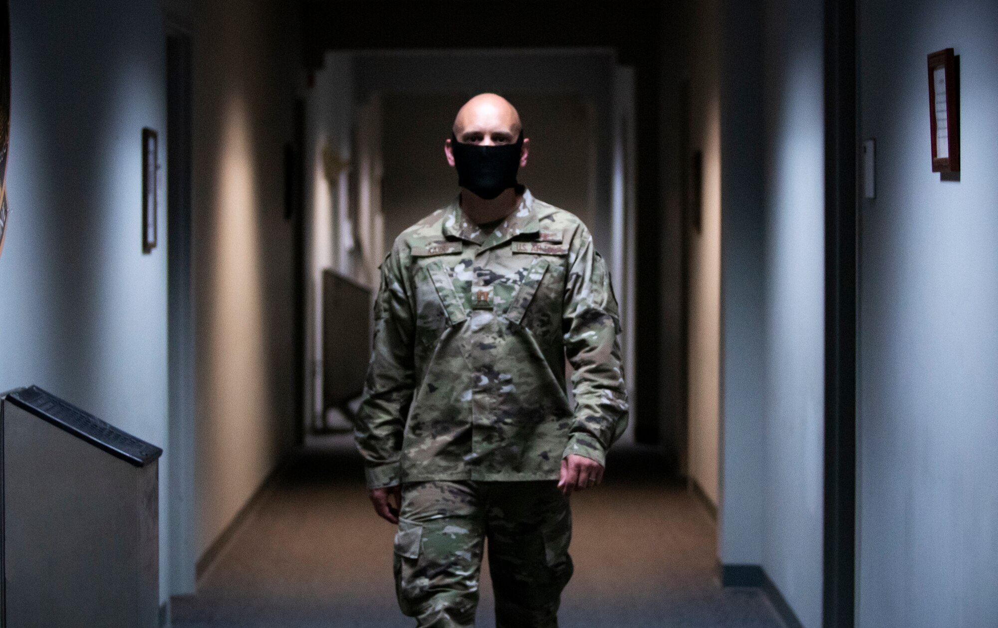 Officer Training School Instructor Capt. Jeremy Karr walks by a temporarily installed portable air-handling unit in a hallway at the school, May 13, 2020, Maxwell Air Force Base, Alabama. Permanent units are being affixed to the HVAC systems in the school’s eight buildings. The air-handling technology, along with the current use of HEPA filters, show promise in decreasing airborne spread of bacterial and viral infectious diseases, such as the coronavirus that causes COVID-19. (Courtesy photo)