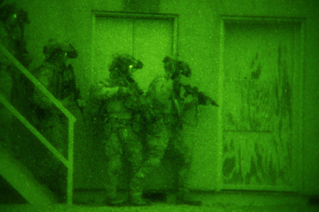 A night-vision goggle view of Airmen approaching a door.
