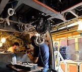 Jonathan Lopez (right) and Michael Lee, aircraft electricians in the assembly repair division at the Corpus Christi Army Depot, Texas, install the data concentrator units wiring as part of the UH-60L to UH-60V helicopter upgrade. (U.S. Army photo by Ervey Martinez)