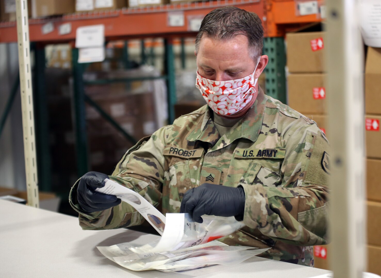 Washington National Guard Sgt. Kevin Probst, 1041st Transportation Company, puts an instruction sheet into the COVID-19 test kit at the Department of Health Warehouse in Tumwater, Washington, May 14, 2020.