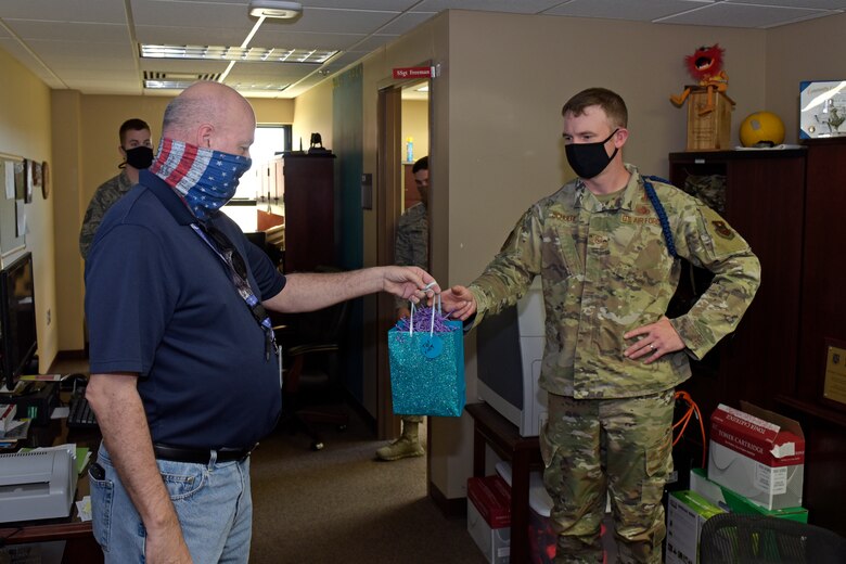 17th Training Wing Community Support Coordinator, David Sullins hands U.S. Air Force Master Sgt. Nicholas Schule, 312th Training Squadron flight chief, a gift bag, as part of the Adopt-An-MTL, in the 312th TRS dormitory on Goodfellow Air Force Base, Texas, May 1, 2020. The Adopt-An-MTL program was created to let the military training leaders know they are not alone and that the Goodfellow family appreciated all they do. (U.S. Air Force photo by Senior Airman Zachary Chapman)