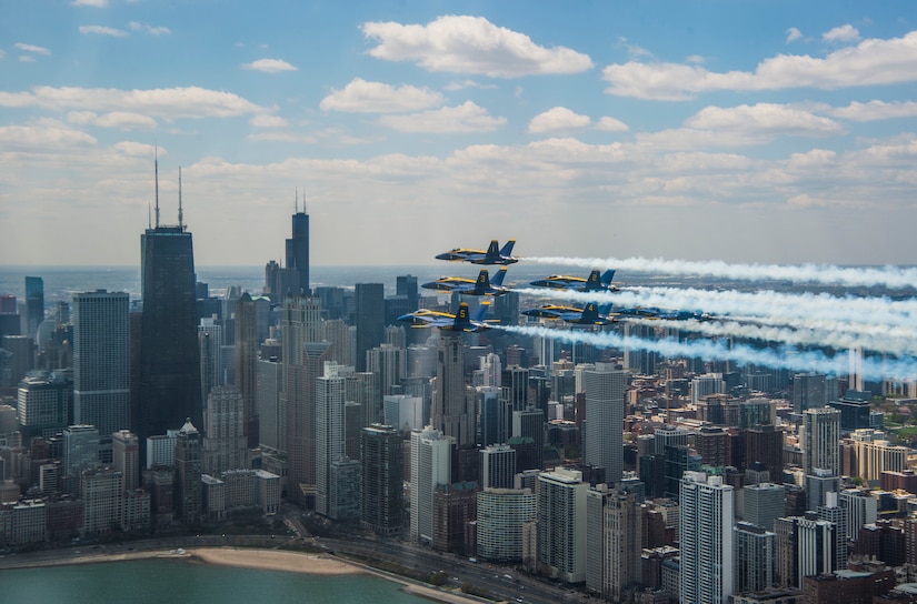 Jets fly over a city with many tall buildings.