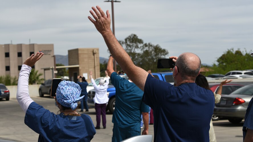 A photo of medical professionals wave at aircraft during a flyover.