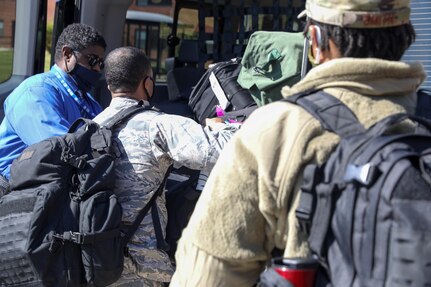 U.S. Air Force Capt. John Nelson (center), psychologist, 59th Medical Group, Randolph Air Force Base, Texas, helps his fellow airmen, including behind Staff Sgt. Le’Aisha Smith (right), mental health technician, 59th Medical Group, Randolph Air Force Base, Texas, by loading up their baggage and personal belongings into the back of the van at Joint Base McGuire-Dix-Lakehurst, NJ, April 28, 2020. Nelson and Smith are a part of a six-member team that will provide behavioral health and support services to the service men and women that are provide care and medical services to COVID-19 patients. U.S. Northern Command, through U.S. Army North, is providing military support to the Federal Emergency Management Agency to help communities in need. (U.S. Army photo by Sgt. Aimee Nordin)