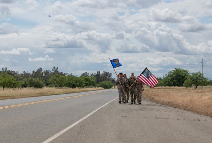 Airmen from the 9th Security Forces Squadron ruck alongside a road while a U-2 flies behind them as part of Police Week.