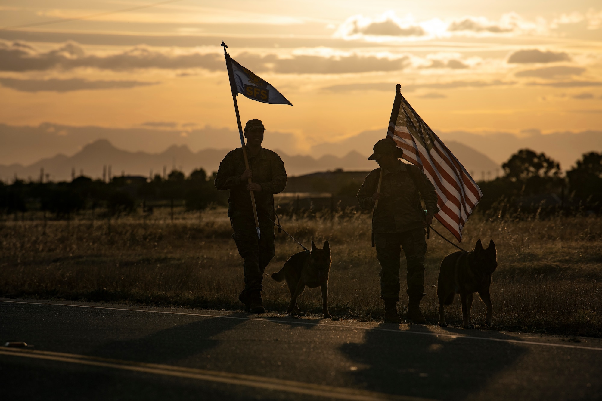 U.S. Air Force Staff Sgt. Sandra Ohfa-Jones, 9th Security Forces Squadron (SFS) trainer, right, and Tech. Sgt. Patrick Harris, 9th SFS commercial vehicle inspection area NCOIC, left, carry the U.S. Flag and 9th SFS guidon as part of Police Week.