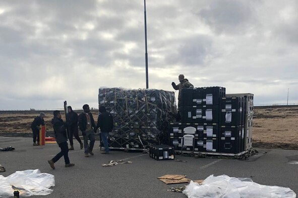 Photo shows large pallets with an assortment of equipment being stack on them for shipment.