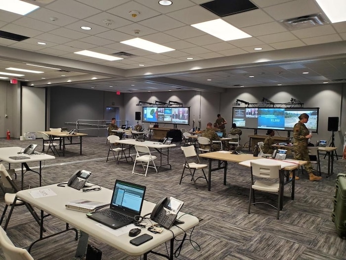 Photo shows large room with tables and laptops being set up.