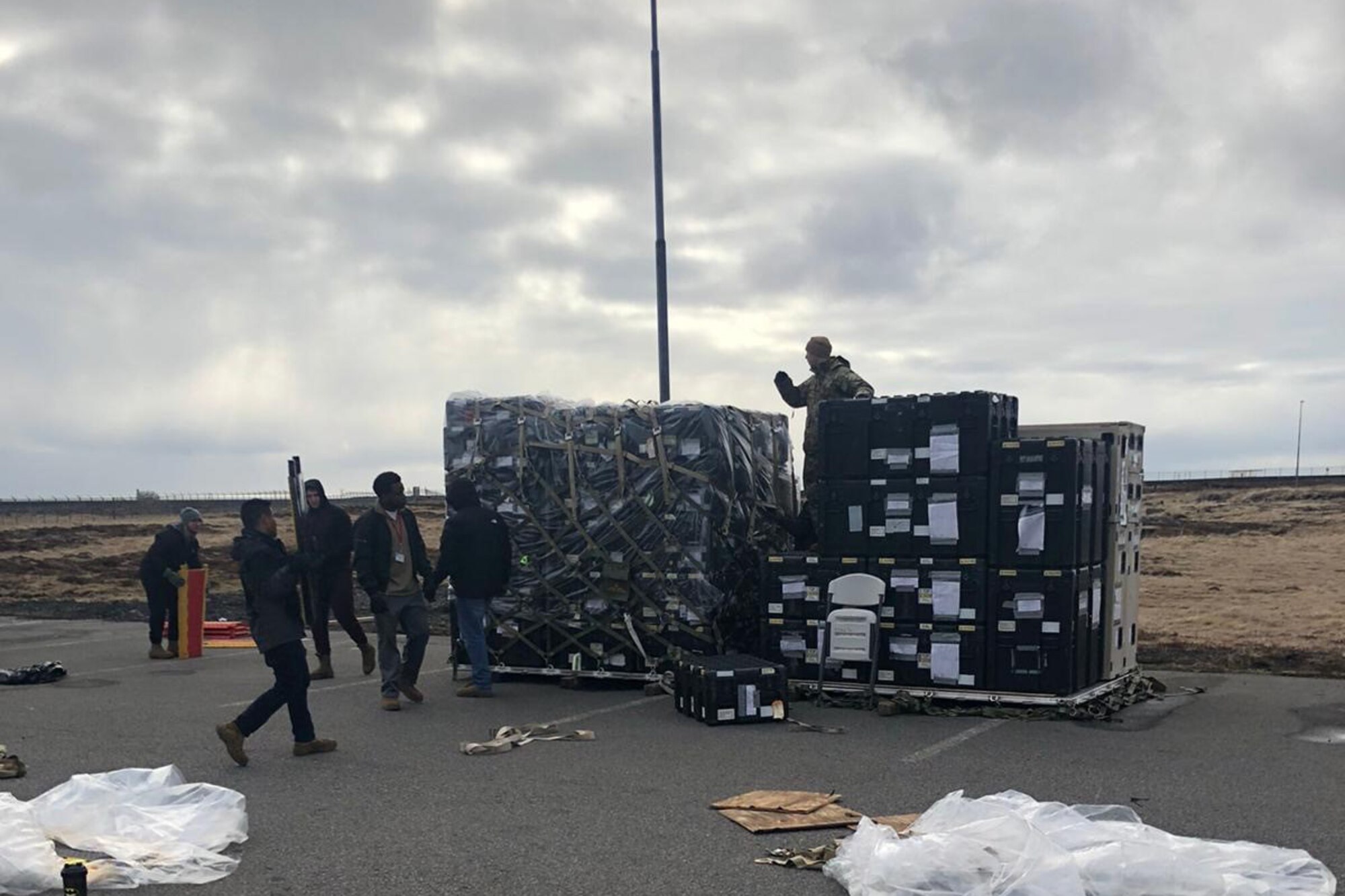 Photo shows large pallets with an assortment of equipment being stack on them for shipment.
