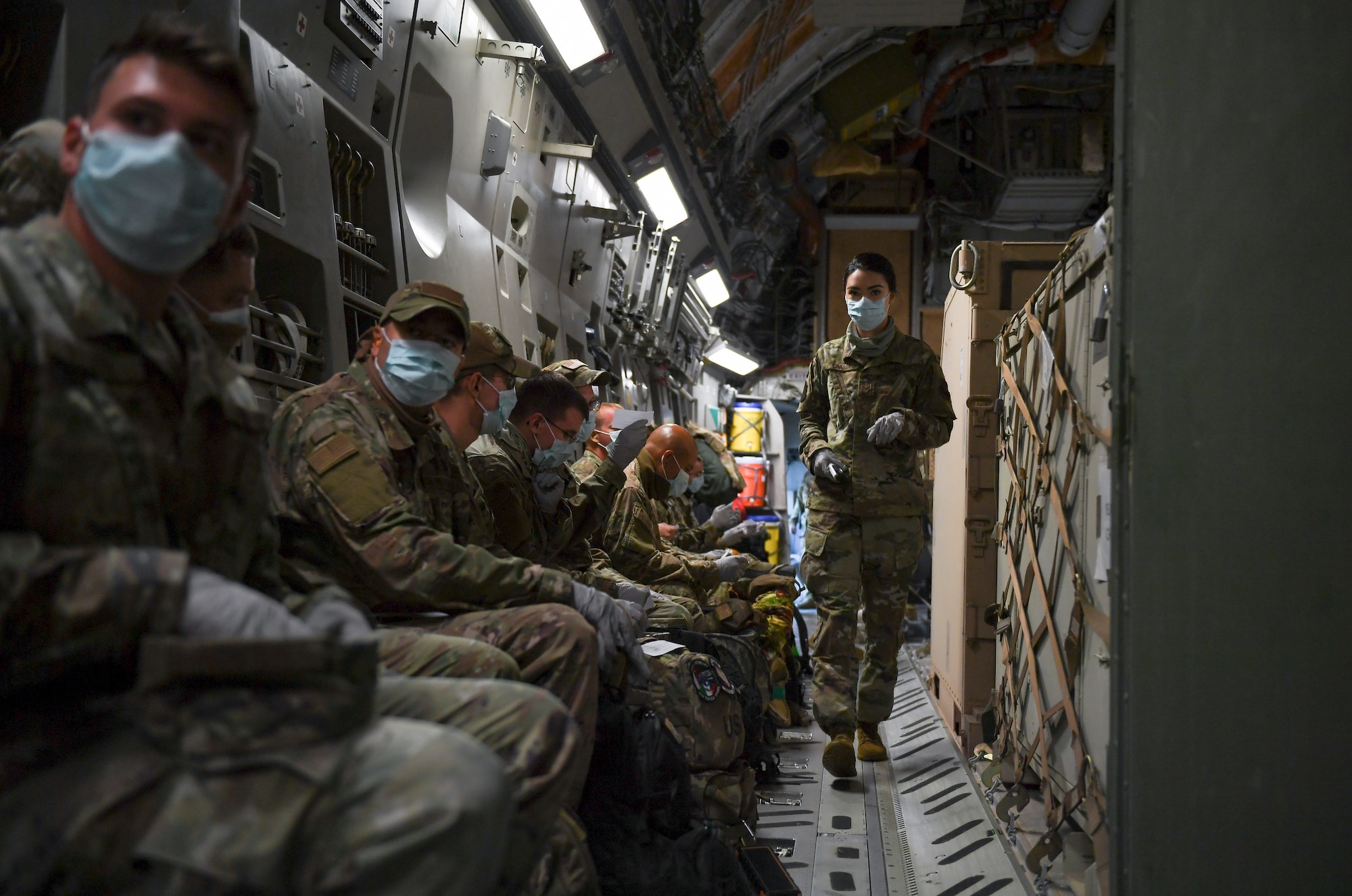 An Airman walking past other Airmen in a plane.
